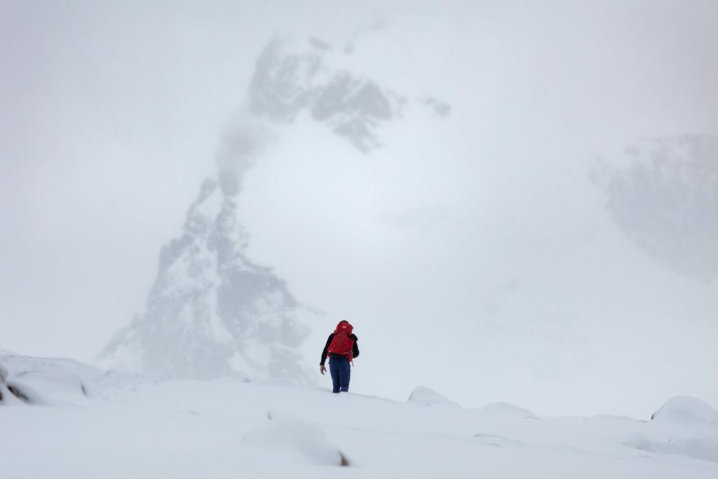 Person hikes in a snowy, mountainous landscape.