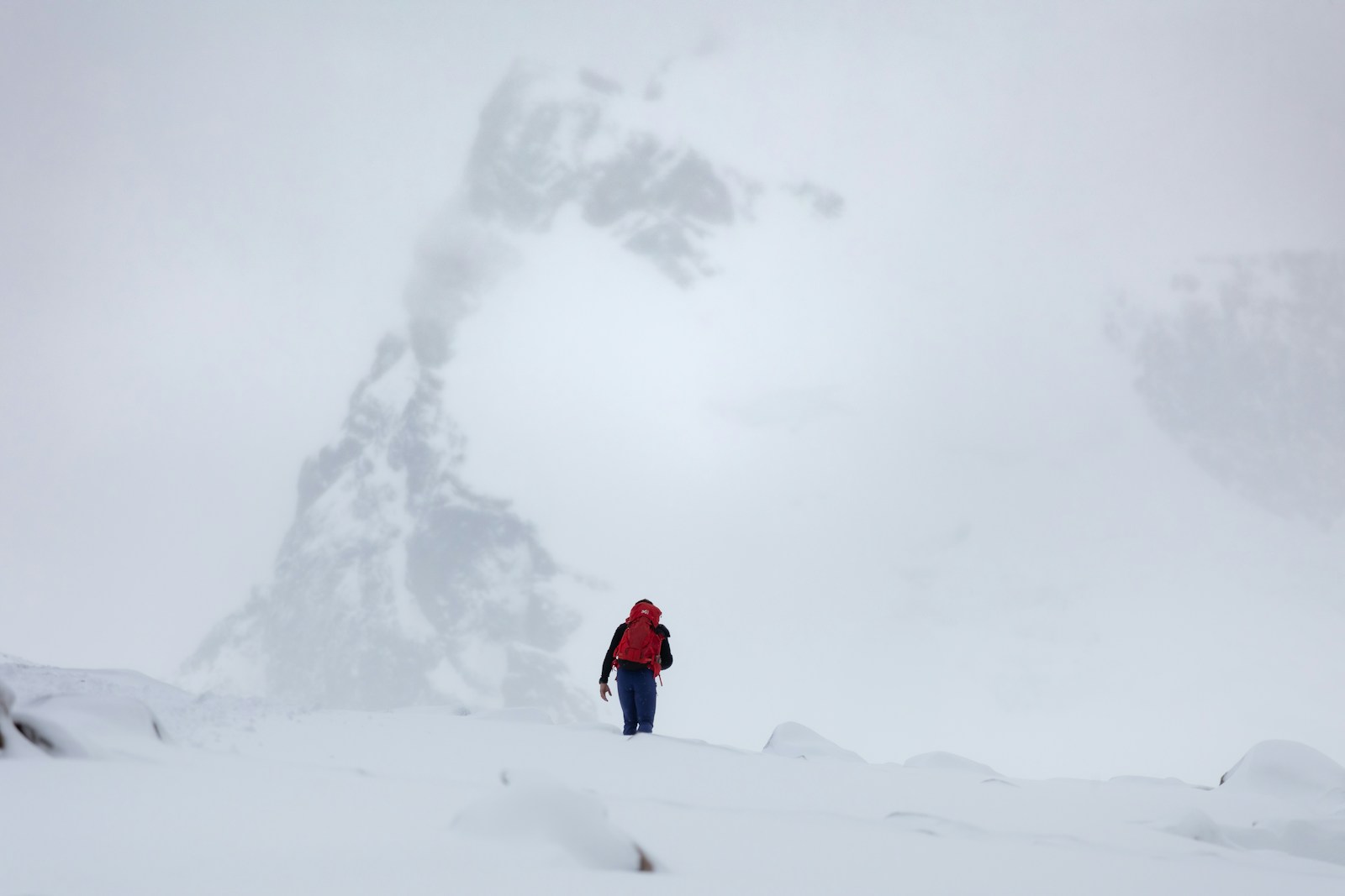 Person hikes in a snowy, mountainous landscape.